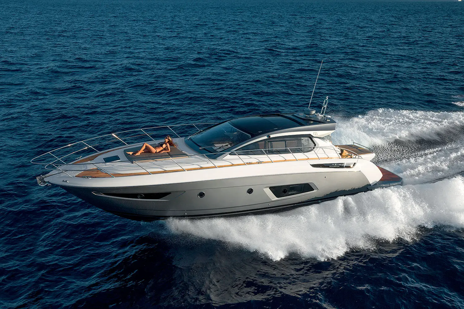 Moderne Motoryacht in Fahrt mit sonnenbadendem Gast auf dem Bugdeck bei einem exklusiven Tagescharter-Erlebnis